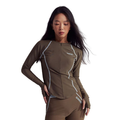 Woman in a brown Speedo Wavechasers 2.0 long-sleeve rashguard with light blue piping and front zipper.