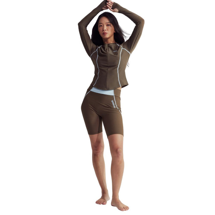 Woman in brown Speedo Wavechasers 2.0 mid-leg swim shorts and matching long-sleeve top with light blue accents.